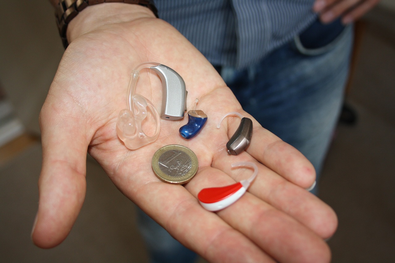 Mn holding some Bluetooth Hearing Aids and Euro Coin